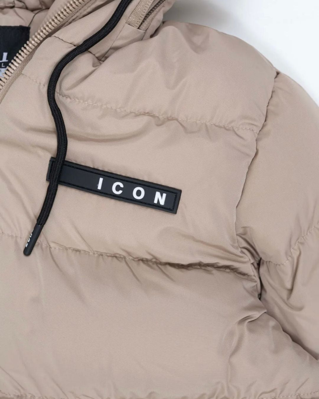 ICON winterjas beige voor jongens – warme fleecegevoerde kinderjas met afritsbare capuchon, sportieve ICON-branding en winddichte ritssluiting. Ideaal voor winterse dagen. Verkrijgbaar in kindermaten. logo